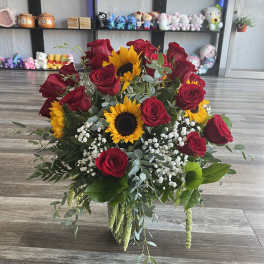 Bouquet of red roses and sunflowers in a glass vase
