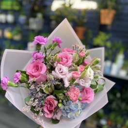Pink rose bouquet with small purple and white flowers wrapped in pale paper