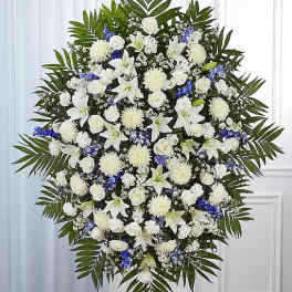 Large white and blue funeral spray with lilies, roses, and palm fronds