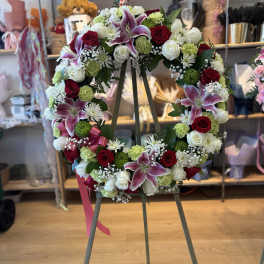 Circular floral wreath on an easel with red, white, and pink blooms