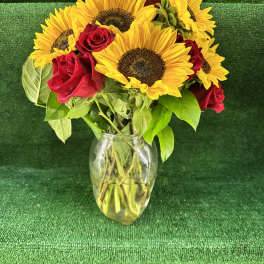 Sunflowers and red roses arranged in a clear glass vase