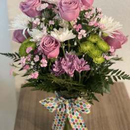 Bouquet of pink roses, white daisies, and green mums in a glass vase
