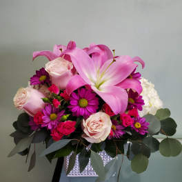 Pink lilies and roses arranged in a square vase