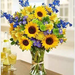 Bouquet of sunflowers and blue flowers in a glass vase