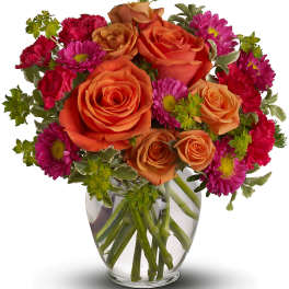 Bouquet of orange roses and magenta daisies in a clear glass vase