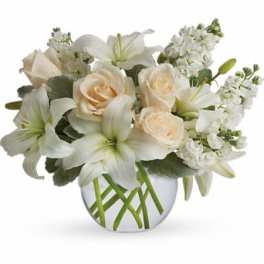 Low arrangement of white lilies and cream roses in a round clear glass vase