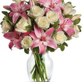 Pink lilies and white roses arranged in a clear glass vase