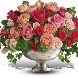 Pink and peach roses arranged in a silver pedestal vase