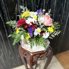 Mixed bouquet with roses and daisies in a square vase