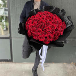 Large bouquet of red roses wrapped in black paper with white ribbon