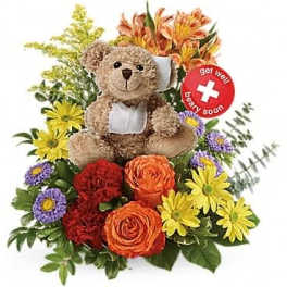 Teddy bear with bandages nestled among bright orange, red, yellow, and purple flowers with a get well sign.