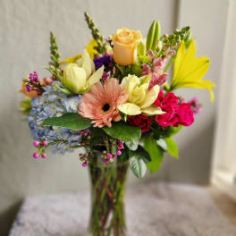 Mixed bouquet in a clear glass vase with roses, gerbera daisy, hydrangea, and lilies