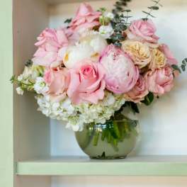 Pink and white flower arrangement in a round glass vase