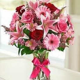 Pink and red mixed bouquet in a glass vase with a pink ribbon