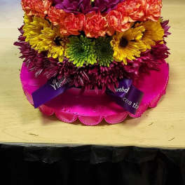 Colorful tiered flower cake with candles on a pink base