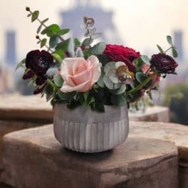 Pink and red roses in a ribbed white vase with eucalyptus