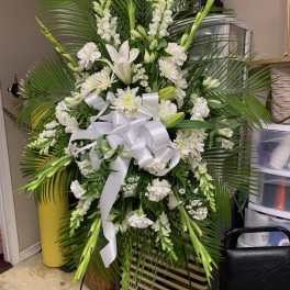 Large white funeral spray with lilies, daisies, and a white ribbon