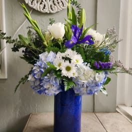 Blue and white floral arrangement in a tall cobalt vase