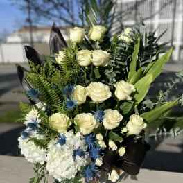 Bouquet of white roses, hydrangeas, and blue thistle in a box