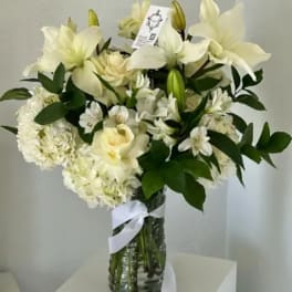 White floral bouquet in a glass vase with a ribbon