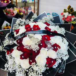 Red and white rose bouquet with baby's breath and a black ribbon