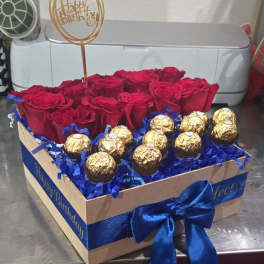 Red roses and gold-wrapped chocolates in a gift box with a birthday topper