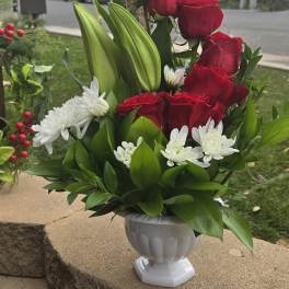 Red roses and white daisies arranged in a white vase