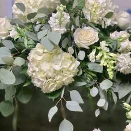 White hydrangeas and roses arranged with eucalyptus greenery