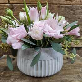 Pink and white flowers arranged in a ribbed white vase