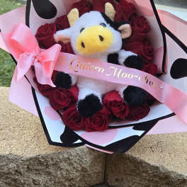 Bouquet of red roses with a plush cow and pink ribbon