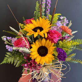 Bouquet of sunflowers, pink roses, and purple flowers in a vase