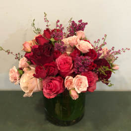 Red and pink roses arranged in a dark glass vase