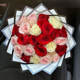 Bouquet of red, pink, and cream roses wrapped in layered paper