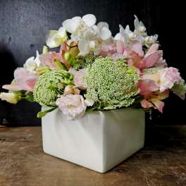 Pink and white floral arrangement in a white square vase