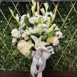 White floral bouquet in a glass vase with a pale ribbon