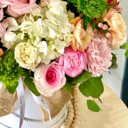 Pink and cream bouquet with roses, hydrangea, and carnations in a wrapped container