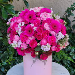 Pink bouquet of roses, ranunculus, and gerbera daisies in a pale pink box