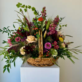 Mixed flower arrangement in a wicker basket with pink, purple, and peach blooms