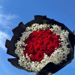 Bouquet of red roses surrounded by white baby's breath in black wrap