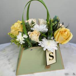 Yellow and white roses with white daisies in a green gift bag