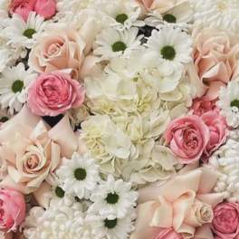 Pink and cream roses with white daisies and hydrangeas in a dense bouquet.