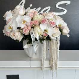 White and blush bouquet of roses and orchids in a white vase