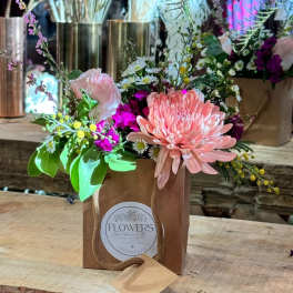 Pink and peach floral arrangement in a pink gift box with a rope handle