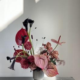 Pink and black floral arrangement in a ribbed vase