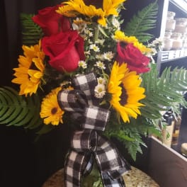 Bouquet of sunflowers and red roses in a glass vase with a plaid ribbon