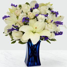 White lilies and roses with purple accents in a blue vase