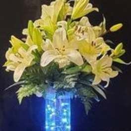 White and yellow lilies arranged in a tall blue vase