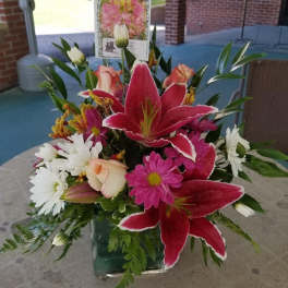Bouquet of pink lilies, white daisies, and roses in a glass vase