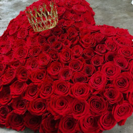 Heart-shaped arrangement of red roses with a gold crown on top