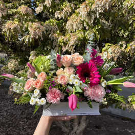Pink and peach flower arrangement in a white box
